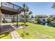 Backyard with pond views, patio, green grass, and palm trees on a sunny day at 7631 Sailwinds Pass, Port Richey, FL 34668