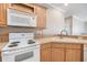 Close-up of kitchen showcasing white appliances, tile backsplash, and wood cabinets at 7631 Sailwinds Pass, Port Richey, FL 34668