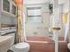 Retro bathroom featuring pink and white tiles, pink bathtub, and patterned shower curtain at 7816 38Th N Ter # 7816, St Petersburg, FL 33709