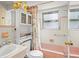 Retro bathroom featuring pink and white tiles, pink bathtub, and vintage cabinet at 7816 38Th N Ter # 7816, St Petersburg, FL 33709
