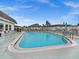 Community pool surrounded by a white fence with lounge chairs and tables and blue umbrellas at 7816 38Th N Ter # 7816, St Petersburg, FL 33709