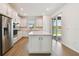 Open-concept kitchen with white cabinetry, stainless steel appliances, a central island, and access to the lanai at 9412 Coastline Way, Parrish, FL 34219