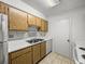 Efficient kitchen design featuring wooden cabinets, a stainless steel sink, and white appliances for a clean look at 13385 Arbor Pointe Cir # 203, Tampa, FL 33617