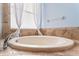 Soaking tub with tile surround, a large window, and a modern faucet, creating a relaxing atmosphere at 16313 Dinsdale Dr, Spring Hill, FL 34610