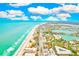 Stunning aerial shot of a beachfront community boasting colorful buildings, pristine sandy shores, and sparkling ocean views at 17940 Gulf Blvd # 2B, Redington Shores, FL 33708