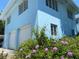 Light blue two story home featuring white garage doors and front yard garden filled with purple flowers at 1800 Pass A Grille Way # 5, St Pete Beach, FL 33706