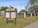 Community entrance sign with manicured landscaping and an American flag at 2009 Hammock Pine Blvd # 2009, Clearwater, FL 33761