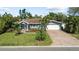 Charming single-story home with a manicured lawn, lush landscaping, and a brick-paved driveway leading to the garage at 2037 Church Creek Pt, Largo, FL 33774