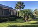 Backyard featuring a screened-in patio and lush green grass, surrounded by palm trees and shrubs at 254 Padova Way, North Venice, FL 34275