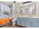 Stylish bathroom with a blue vanity, dual sinks, and a vibrant shower curtain at 31123 Stone Arch Ave, Wesley Chapel, FL 33545