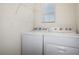 Efficient laundry room with modern white washer and dryer, complemented by a wire shelf and bright window at 3135 Suncoast Blend Dr, Odessa, FL 33556