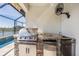 Built-in outdoor kitchen featuring a stainless steel grill, stone accents, and poolside convenience at 33899 Astoria Cir, Wesley Chapel, FL 33545