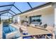 Spacious screened-in patio featuring a full outdoor kitchen, dining, and lounge areas by the pool at 33899 Astoria Cir, Wesley Chapel, FL 33545
