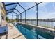 Tranquil in-ground pool area with a cascading waterfall, a screened enclosure, and beautiful lake views at 33899 Astoria Cir, Wesley Chapel, FL 33545
