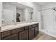 Bathroom featuring double sinks, dark cabinetry, and a shower with a glass enclosure at 35592 Stella Vast Dr, Zephyrhills, FL 33541