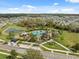 Aerial view of a community pool, playground, and clubhouse surrounded by palm trees and green spaces at 35592 Stella Vast Dr, Zephyrhills, FL 33541