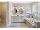Bright bathroom with double vanity, oval mirrors, soaking tub, and tiled walls at 3991 Mellon Dr, Odessa, FL 33556