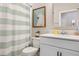 A well-lit bathroom is shown with a sink, toilet, mirror and striped shower curtain at 3991 Mellon Dr, Odessa, FL 33556