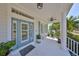 Inviting front porch with white columns and ample seating with tropical landscaping at 413 Islebay Dr, Apollo Beach, FL 33572