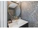 This powder room features a round mirror, gold fixtures, and gorgeous black and gold wallpaper at 4966 Coquina Key Se Dr # 4966, St Petersburg, FL 33705