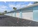 Row of blue garages with white doors and black asphalt driveway under a blue sky at 4966 Coquina Key Se Dr # 4966, St Petersburg, FL 33705