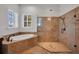 Bright bathroom showcasing soaking tub, glass shower, white shutters and travertine flooring at 5321 Fishersound Ln, Apollo Beach, FL 33572