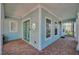 Charming front porch featuring green doors, white columns, and brick flooring at 5321 Fishersound Ln, Apollo Beach, FL 33572