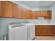 Well-lit laundry room with wooden cabinets, white backsplash, sink and new, modern washer and dryer at 5321 Fishersound Ln, Apollo Beach, FL 33572