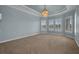 Bright primary bedroom features a tray ceiling, chandelier, neutral carpet, and plantation shutters at 5321 Fishersound Ln, Apollo Beach, FL 33572