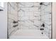 Modern bathroom featuring stylish marble tiled walls, a white tub, and sleek black fixtures at 5419 Cyril Dr, Dade City, FL 33523