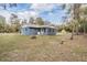 Quaint blue home showcasing a screened porch and a tranquil backyard surrounded by mature trees at 5419 Cyril Dr, Dade City, FL 33523