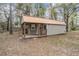 Charming cottage featuring a metal roof, cozy porch, and a serene setting surrounded by mature trees at 5419 Cyril Dr, Dade City, FL 33523