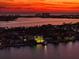 Sunset aerial view of waterfront homes, showcasing stunning coastline and city lights in the distance at 6976 S Shore S Dr, St Petersburg, FL 33707