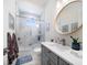 Stylish bathroom featuring a tub and shower with tiled surround, vanity, and round mirror at 6976 S Shore S Dr, St Petersburg, FL 33707