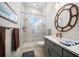Stylish bathroom featuring a glass-enclosed shower, gray vanity with dual sinks and a striking round mirror at 6976 S Shore S Dr, St Petersburg, FL 33707