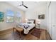 Bright bedroom with two windows, ceiling fan, wood floors, a queen bed, bench and neutral decor at 6976 S Shore S Dr, St Petersburg, FL 33707