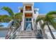 Modern home with a striking entrance, featuring a grand staircase, contemporary design, and lush palm trees at 6976 S Shore S Dr, St Petersburg, FL 33707