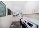 Bright laundry room with white cabinetry, stone countertops, a sink and a modern front-loading washer and dryer at 6976 S Shore S Dr, St Petersburg, FL 33707