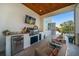 Outdoor kitchen with stainless steel grill, granite countertop, mini-fridge, and a wall-mounted TV at 6976 S Shore S Dr, St Petersburg, FL 33707