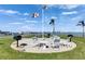 Outdoor seating area featuring picnic tables, chairs, grills, and flag pole with waterfront backdrop at 1 Key Capri # 604W, Treasure Island, FL 33706