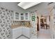 Corner kitchen area showing white cabinets, countertops, and wallpaper near dining space and a hallway at 1 Key Capri # 604W, Treasure Island, FL 33706