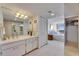 Bathroom featuring a vanity with white cabinets, decorative mirrors, and access to the main bedroom at 1 Key Capri # 604W, Treasure Island, FL 33706