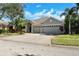 Inviting home exterior with a three-car garage, lush landscaping, and a well-manicured lawn at 10632 Weybridge Dr, Tampa, FL 33626