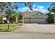 Inviting home exterior with a three-car garage, lush landscaping, and a well-manicured lawn at 10632 Weybridge Dr, Tampa, FL 33626