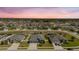 Aerial view of a residential neighborhood showcasing well-maintained homes with manicured lawns against a colorful sunset backdrop at 12749 Weatherstone Dr, Spring Hill, FL 34609