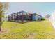 Expansive backyard featuring a screened-in patio, lush green lawn, and privacy fence at 12749 Weatherstone Dr, Spring Hill, FL 34609