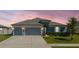 Inviting two-car garage home with neatly trimmed landscaping and a freshly paved driveway beneath a vibrant, colorful sky at 12749 Weatherstone Dr, Spring Hill, FL 34609