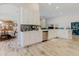 Bright, open-concept kitchen with white cabinets, stainless steel appliances, and wood-look tile flooring at 12749 Weatherstone Dr, Spring Hill, FL 34609