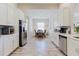 Bright kitchen and dining area featuring white cabinets, stainless steel appliances, and wood-look tile flooring at 12749 Weatherstone Dr, Spring Hill, FL 34609