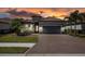 Inviting single-story home with a paver driveway, manicured lawn, with a sunset sky at 12835 Sorrento Way, Bradenton, FL 34211